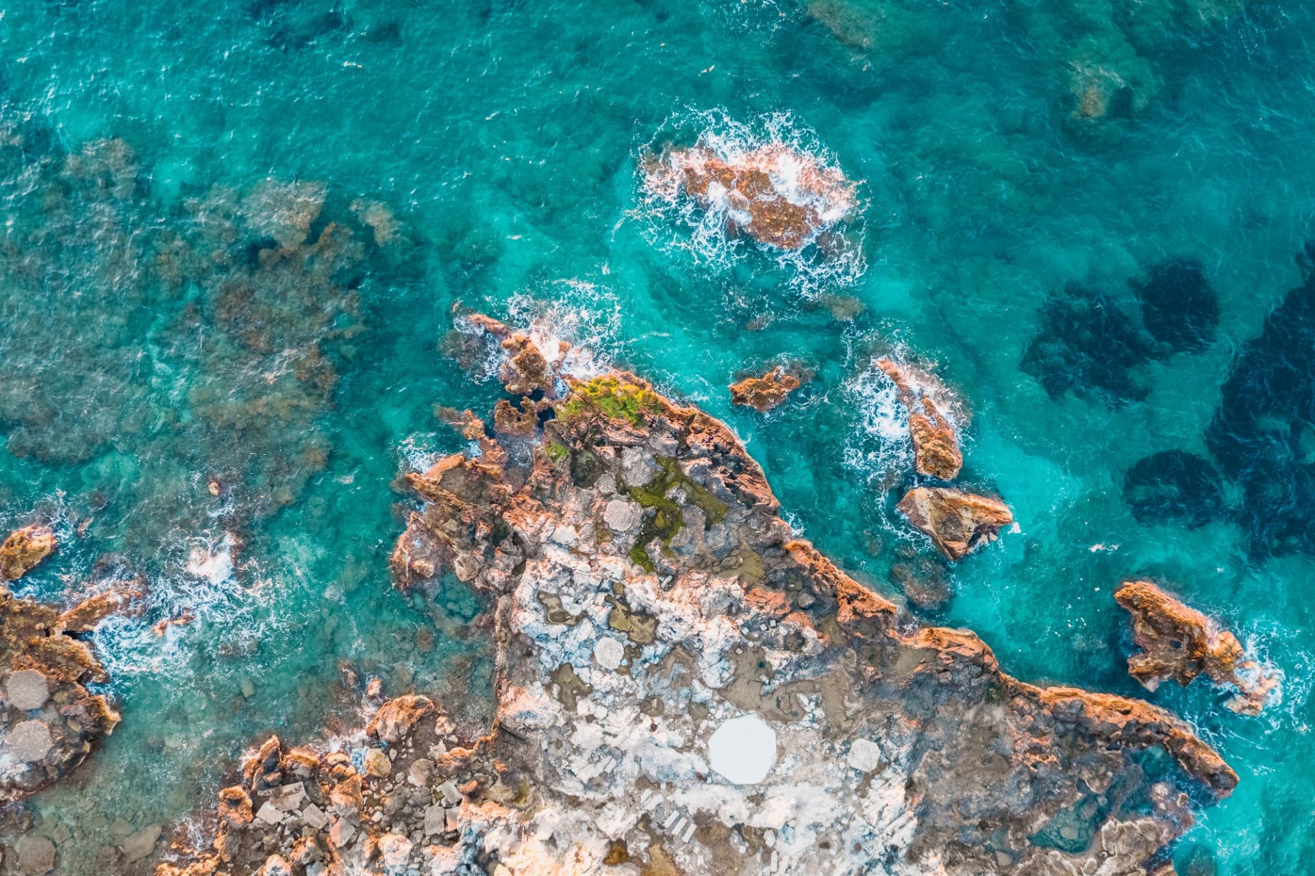 Aerial view of rocks surrounded by clear turquoise water